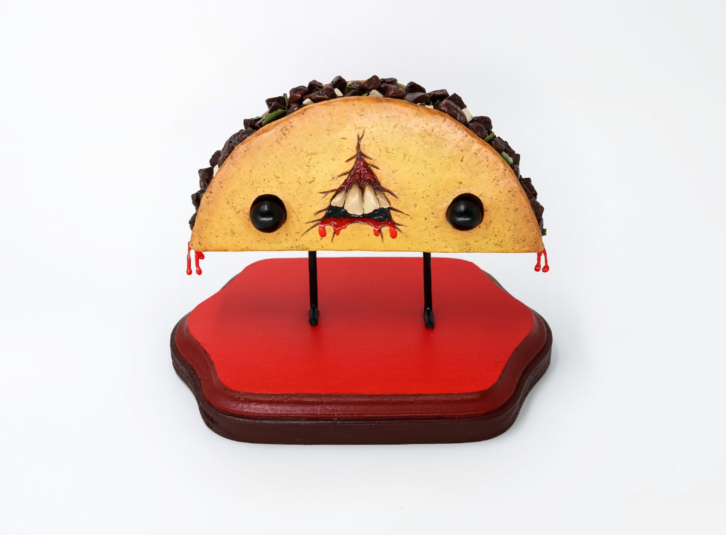 Handmade clay taco sculpture with monster face and dripping red sauce